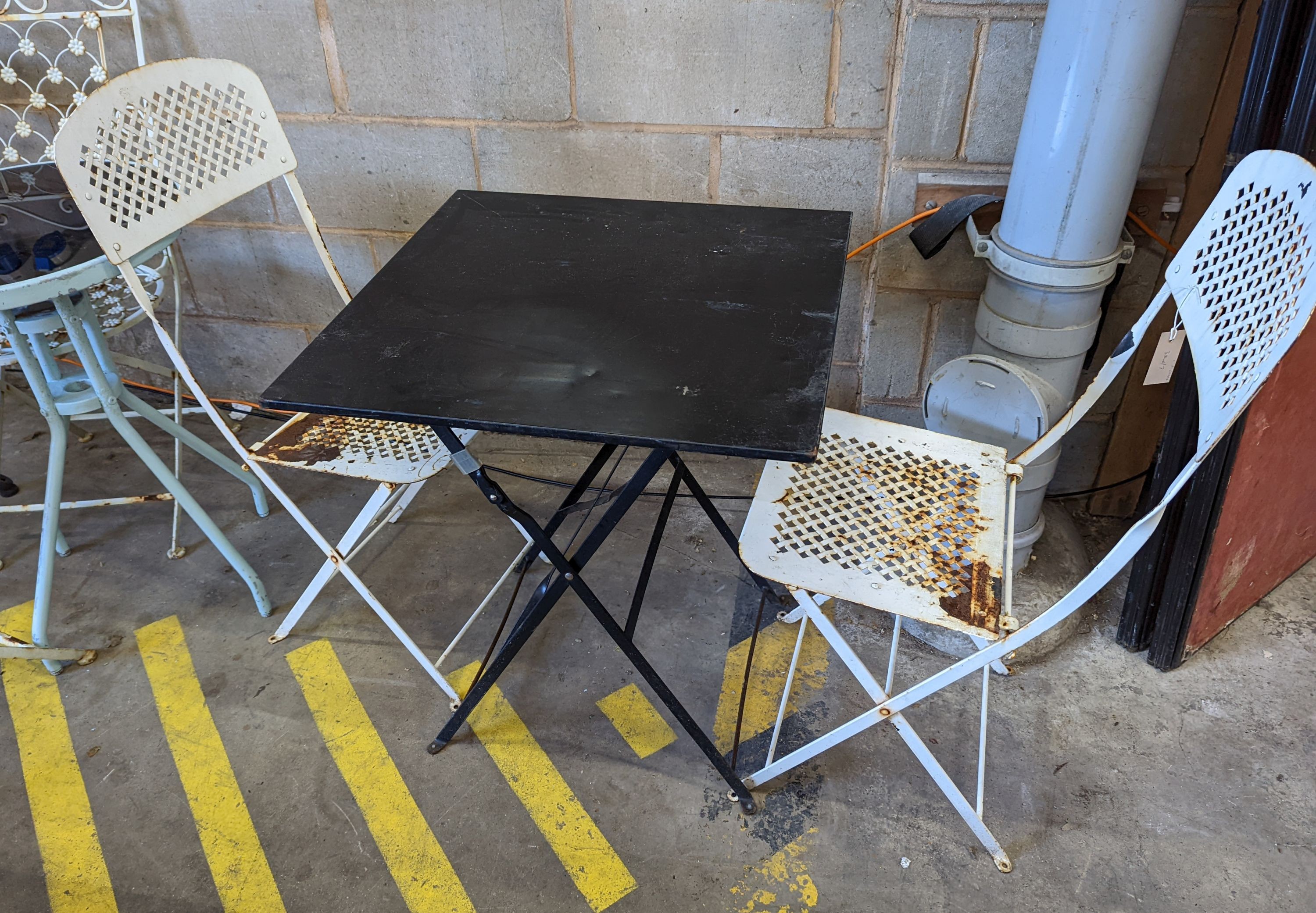 A square metal folding bistro table, width 60cm, height 71cm, together with two metal chairs